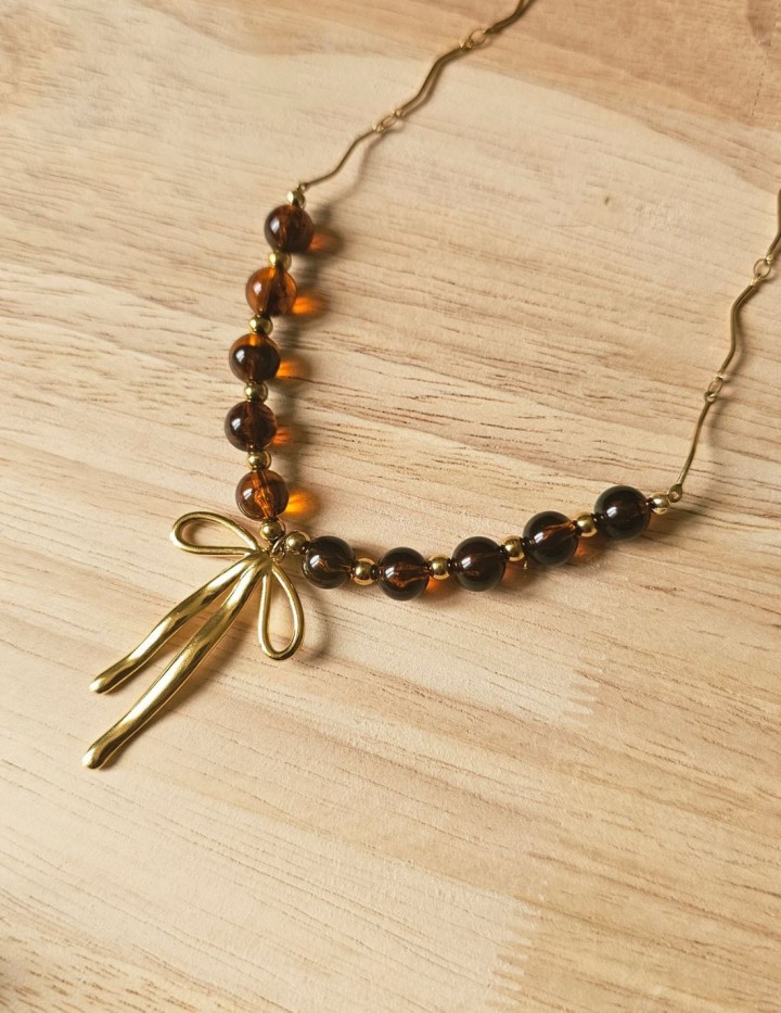 Collier Éloïse à perles brunes translucides, chaîne dorée ondulée et pendentif nœud doré